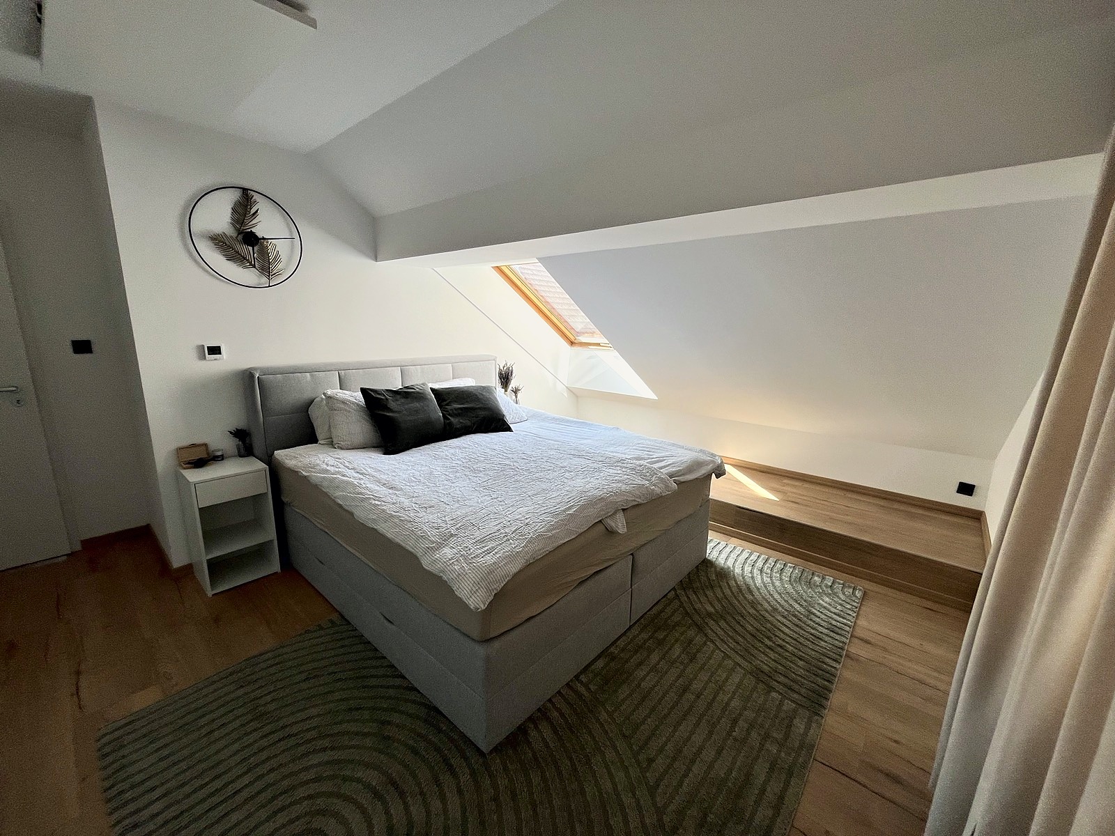 The master bedroom under the single-pitch slope, a roof skylight letting in morning light