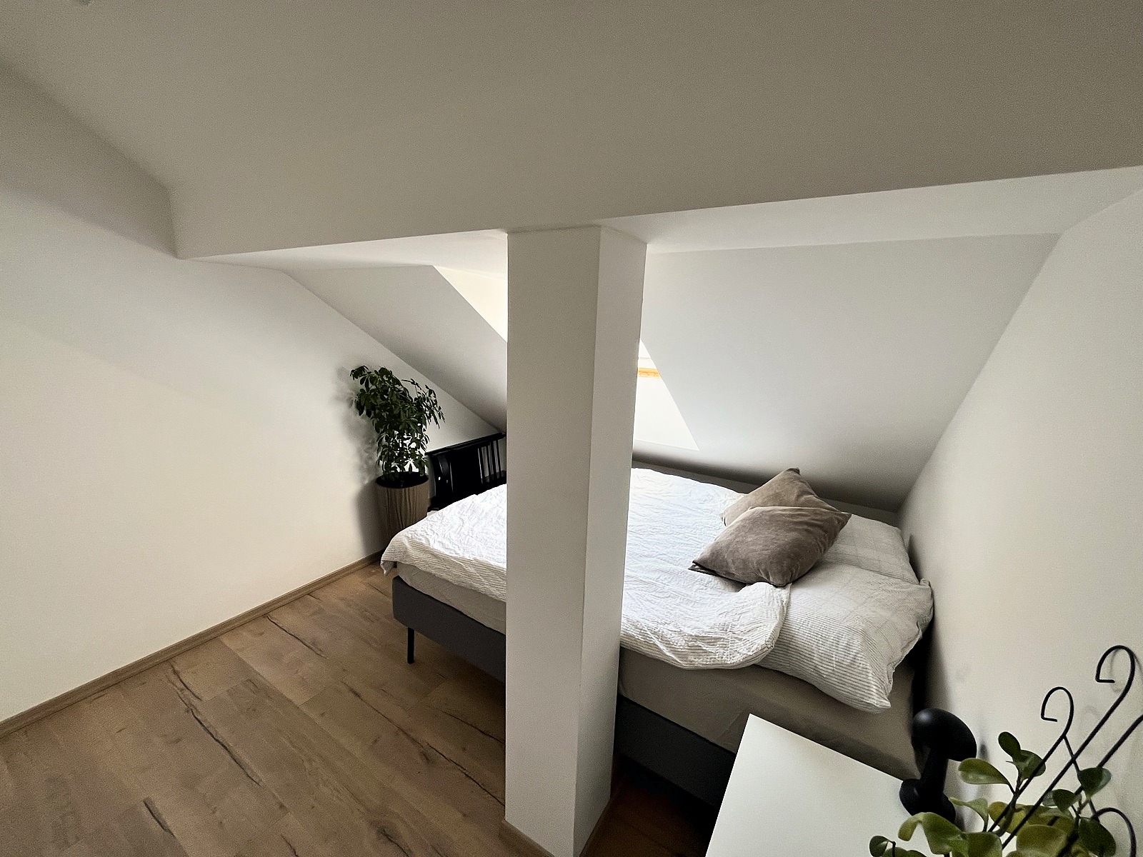 A bedroom tucked under the sloped attic roof, a skylight above the bed
